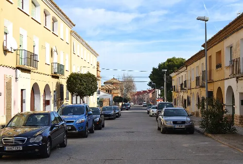 Street with colorful buildings and parked cars in Belchite.