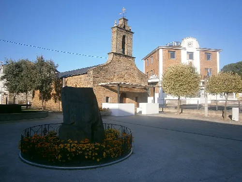Kapelle San Roque und Rathaus mit Bäumen und Denkmal im Vordergrund.