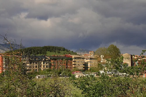 View of buildings and mountains in Guardo, Palencia, with cloudy sky.
