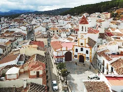 Vista aérea de calles y casas blancas en Villanueva del Trabuco con iglesia en primer plano.