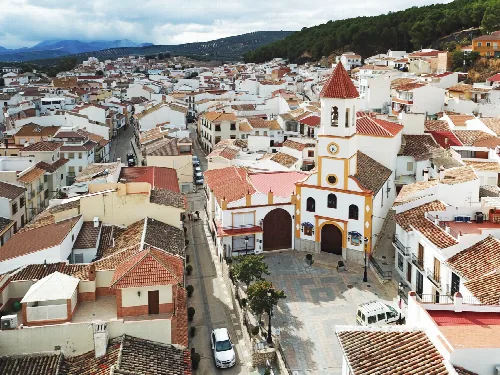 Luftaufnahme von Straßen und weißen Häusern in Villanueva del Trabuco mit Kirche im Vordergrund.