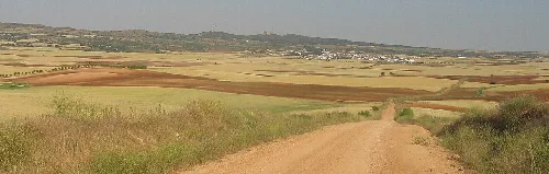 Landschaft mit Dorf und Bergen im Hintergrund von einer Landstraße aus.