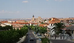 Straßen von Bargas mit Bäumen, Gebäuden und einer Kirche im Hintergrund.