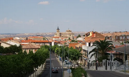 Bargas streets with trees, buildings, and a church in the background.