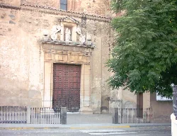 Facade of a church with a wooden door and sculpture on top.