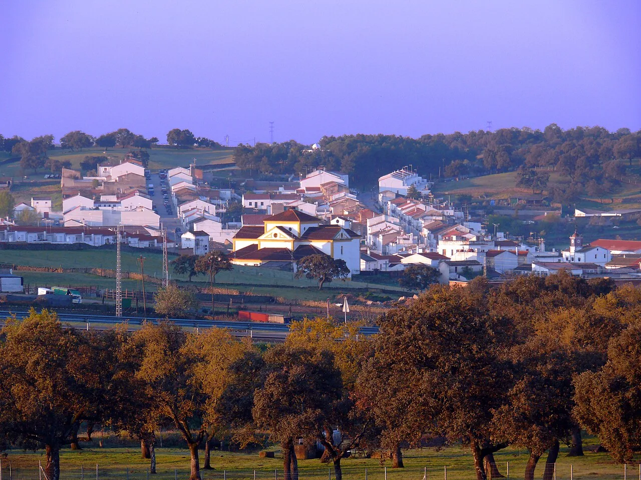 Blick auf Cardeña bei Sonnenaufgang mit weißen Häusern und Bäumen im Vordergrund.