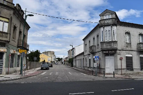 Straße in Láncara mit Eckgebäude und Verkehrsschildern.