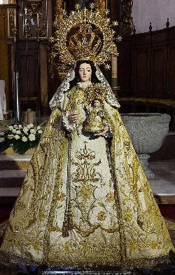 Estatua de la Virgen del Monte con corona y vestido dorado en una iglesia.