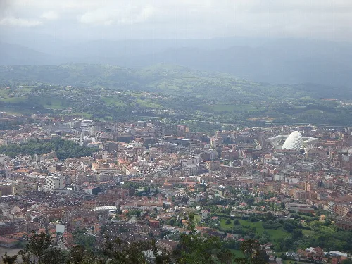 Vista panorámica de Oviedo vista desde el Naranco con edificios y montañas en el fondo.