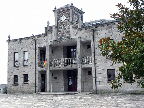 Steinernes Rathausgebäude mit Uhr und Wappen.