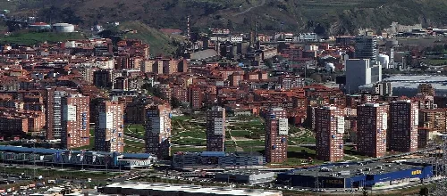 Vista aérea de torres de San Vicente con ciudad y montañas al fondo.