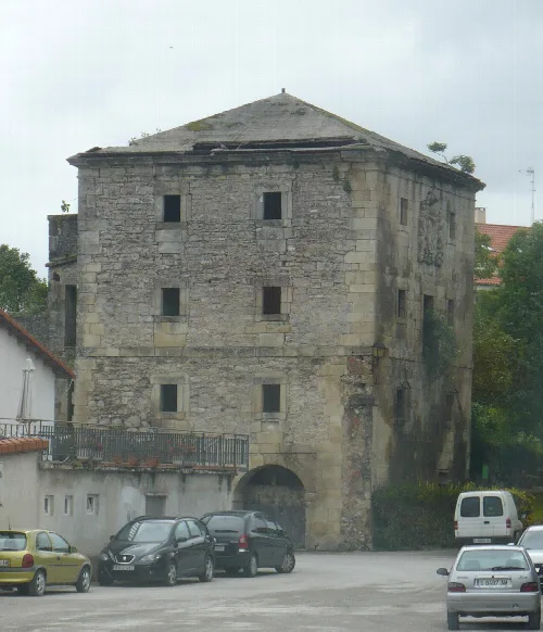 Torre de piedra con varias ventanas y un arco en la planta baja en Ribamontán al Monte.
