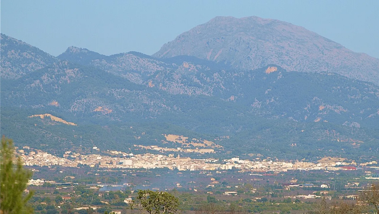 Landscape with town and mountains in the background.