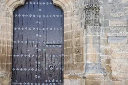 Puerta de madera con detalles metálicos y arco de piedra en Sabiote.