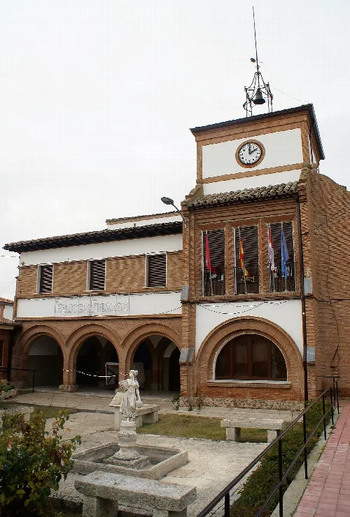 Town hall building with clock and flags on the facade.