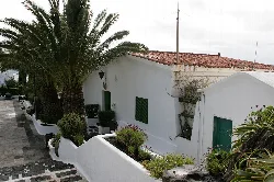 White house with red-tiled roof and plants on the terrace.