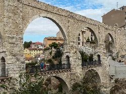 Stone aqueduct with arches in Teruel, with people walking.