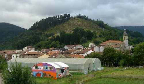 Vista de Villaro, con casas, iglesia y colinas verdes.