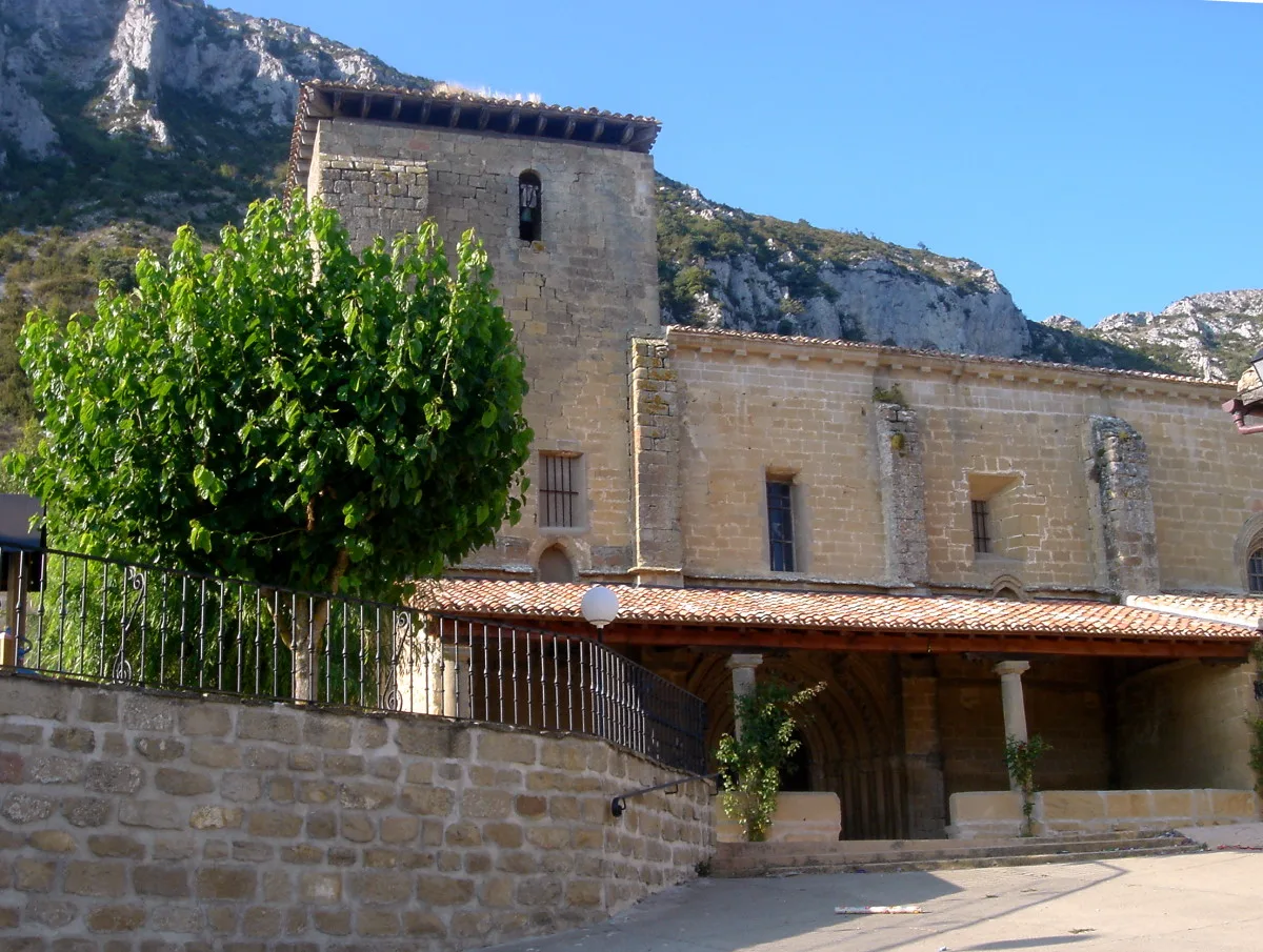 Stone church in Lapoblación with tree and mountains in the background.
