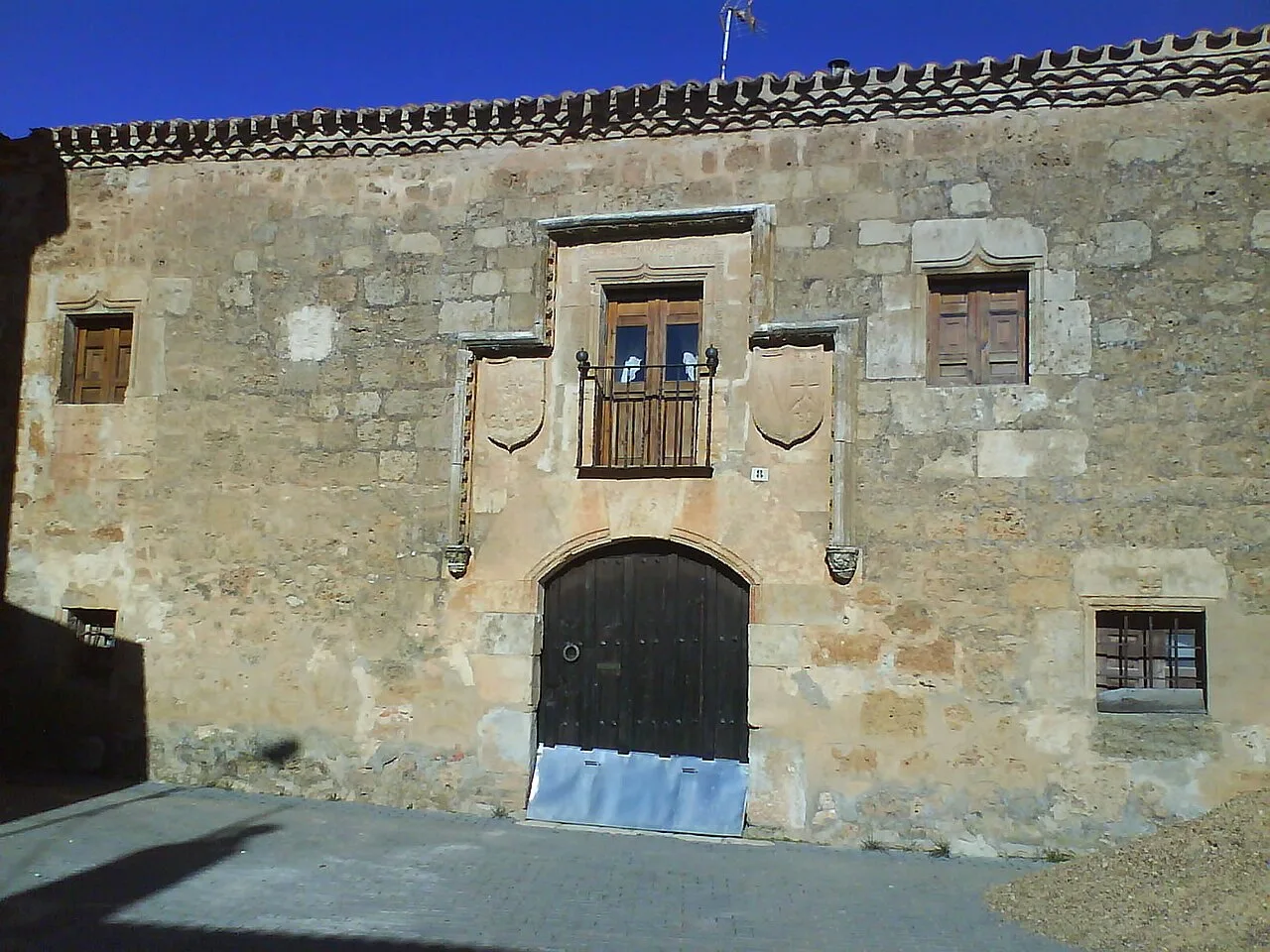 Steinfassade mit Bogen-Tür und kleinen Fenstern in Fuente Pinilla.