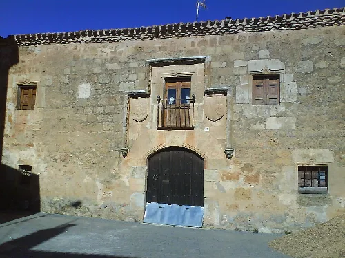 Steinfassade mit Bogen-Tür und kleinen Fenstern in Fuente Pinilla.