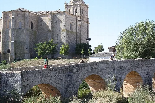 Stone bridge with arches and church in the background in Villasandino.