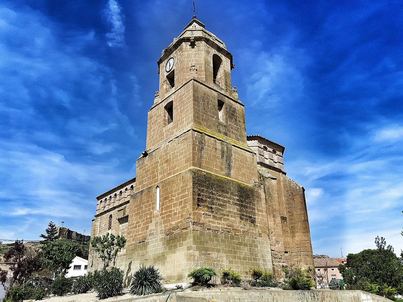 Steinerner Turm mit Uhr und hellem blauen Himmel.