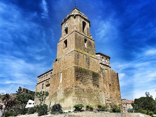 Steinerner Turm mit Uhr und hellem blauen Himmel.