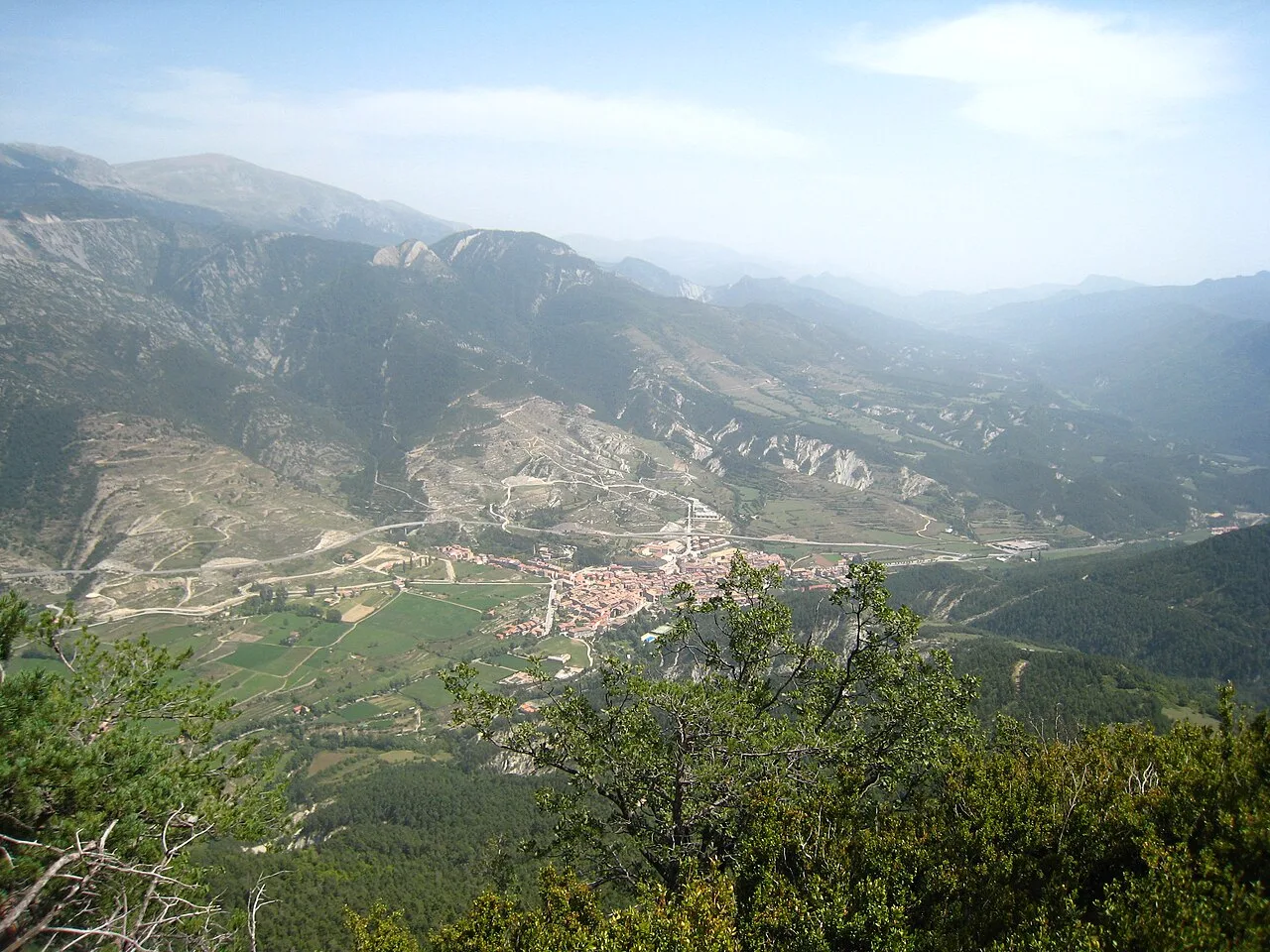 Mountain landscape with Bagà town and greenery in the foreground.