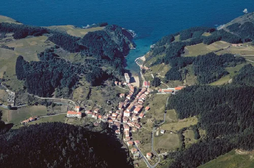 Vista aérea de Ea, con casas, montañas y mar en el fondo.