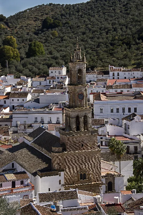 Torre del reloj en Constantina con casas blancas y colinas verdes.