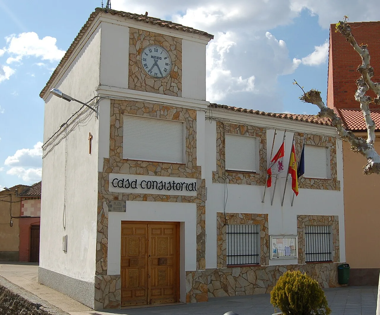 White building with clock and flags on the facade.