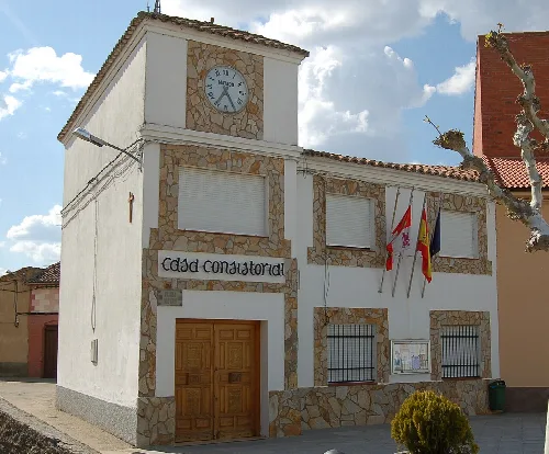 Weißes Gebäude mit Uhr und Flaggen an der Fassade.