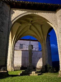 Kreuz auf dem Kirchenbogen in Eulate, Navarra, mit blauem Himmel im Hintergrund.