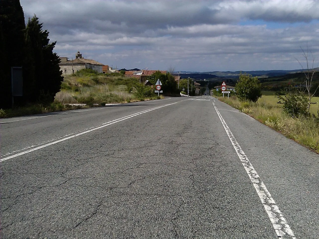 Road with white markings and houses in the distance in Navarra.