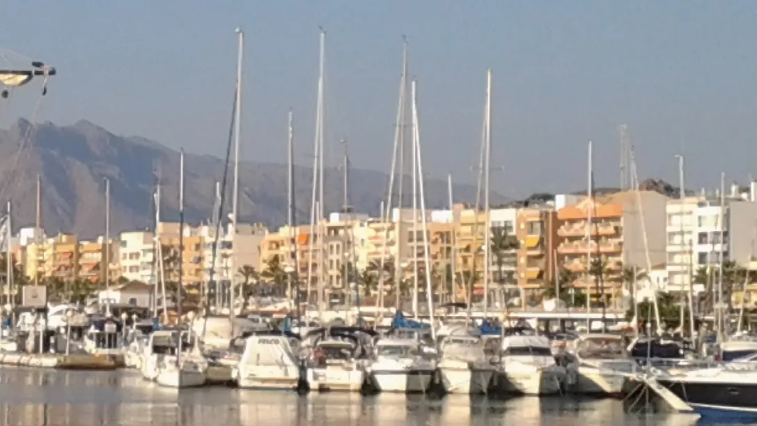 Boote im Hafen von Garrucha mit Gebäuden und Bergen im Hintergrund.