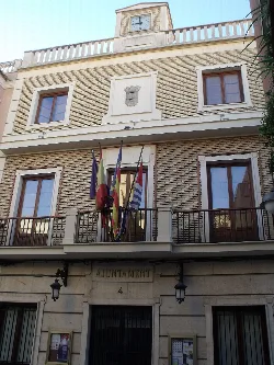 Fassade des Rathauses mit Flaggen und Uhr oben.