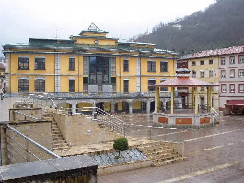 Edificio del ayuntamiento en Sotrondio con plaza y fuente en primer plano.