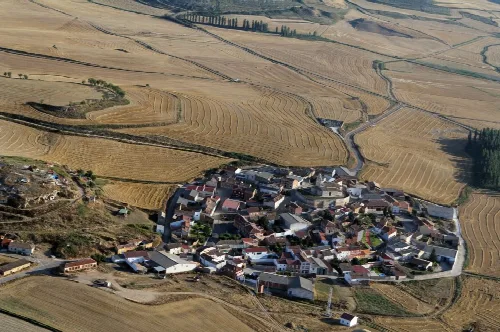 Aerial view of a small village surrounded by agricultural fields in Palencia
