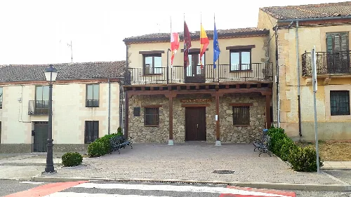 Town hall building with flags and stone entrance in Santo Domingo de Pirón.