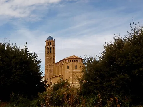 Santa Ana Church in Mainar with bell tower and surrounding vegetation.