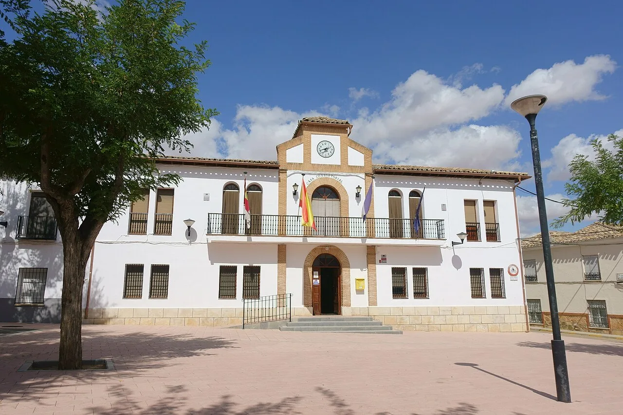 White town hall building with clock and flags in Cabezamesada.
