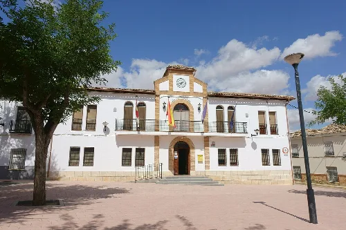 White town hall building with clock and flags in Cabezamesada.