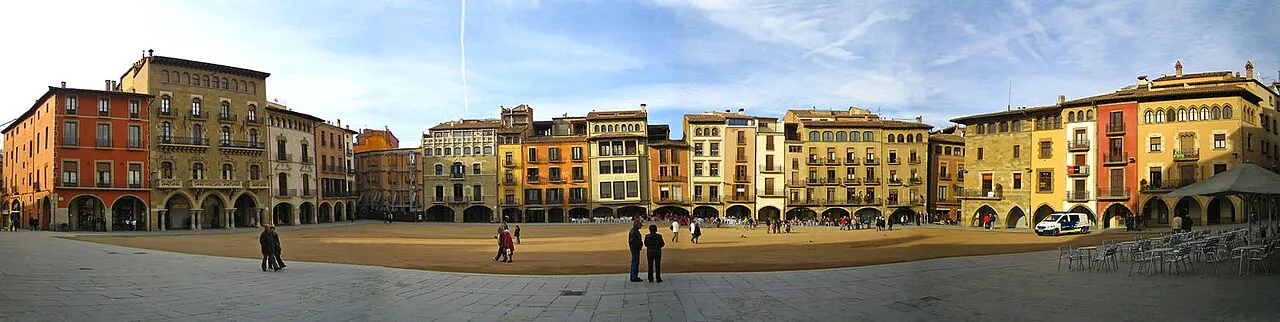 Panoramablick auf den Hauptplatz von Vic mit historischen Gebäuden und Fußgängern.