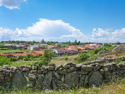 Panoramic view of La Vídola with houses and a stone wall in the foreground.