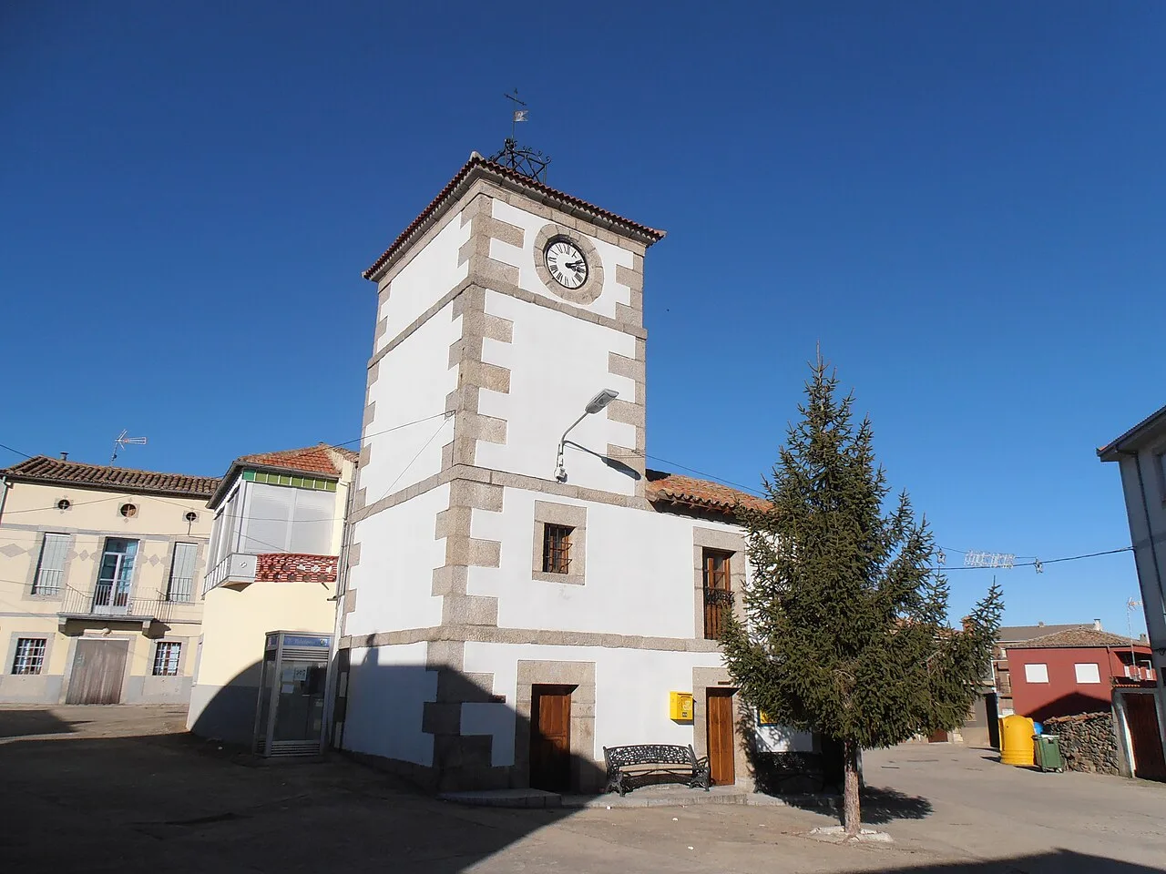 Torre con reloj municipal y árbol en la plaza de Santibáñez de Béjar.