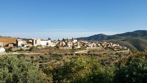 View of white houses on a hill with mountains in the background.