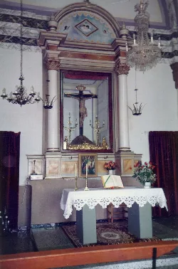 Altar con imagen del Cristo de la Salud, rodeado de candelabros y flores.
