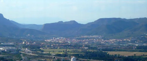 Landschaft mit Stadt und Bergen im Hintergrund.