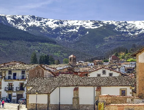 Traditional houses in Candelario with snow-capped mountains behind.